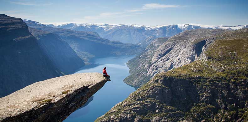 personne au bord d'un rocher fjords Norvège