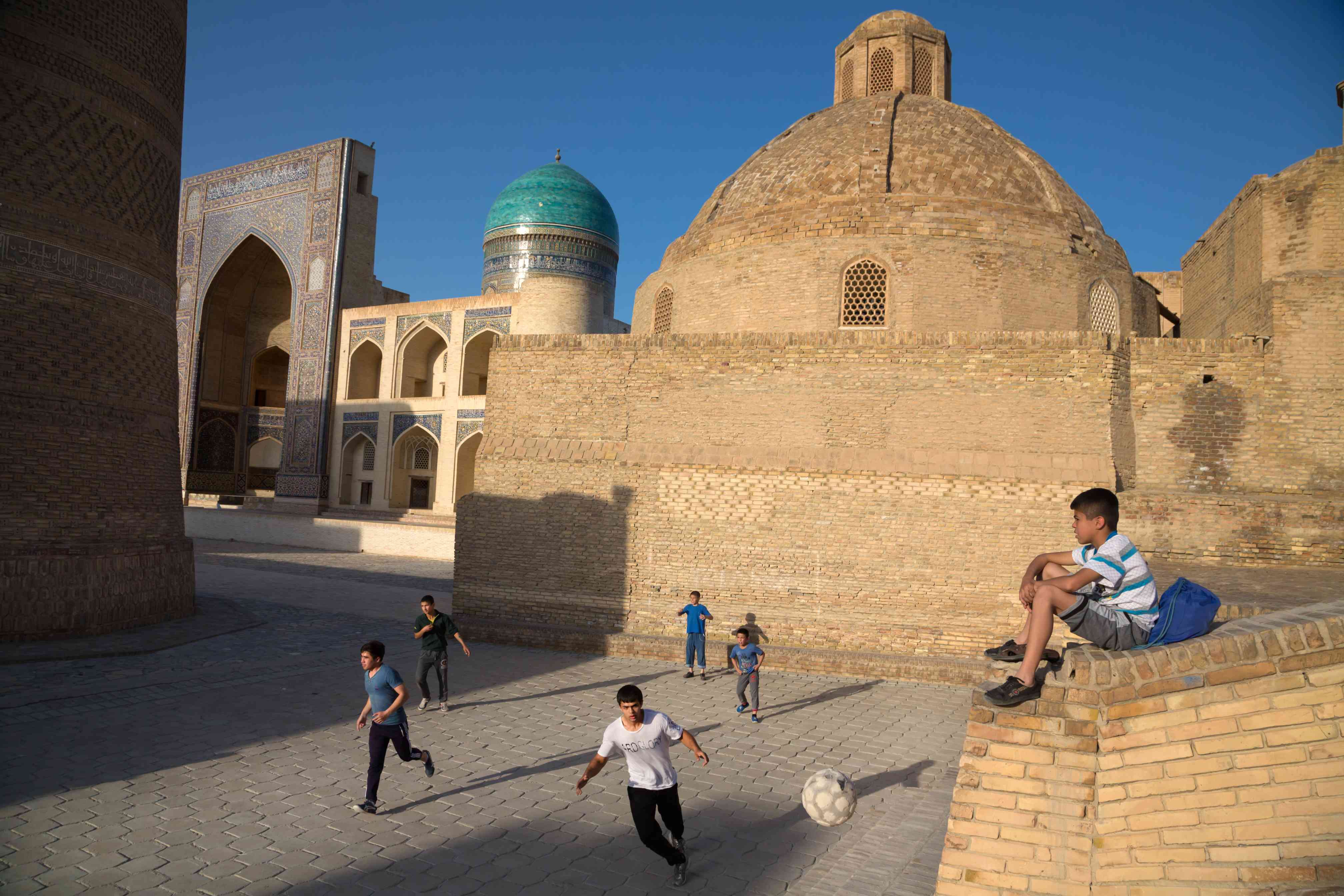 Des adolescents jouent au football dans la vieille ville de Boukhara.